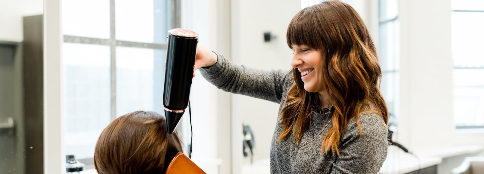 woman blow drying hair in salon.