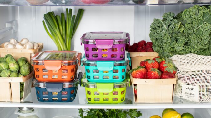 fresh vegetables and tomatoes on a shelf in a fridge.