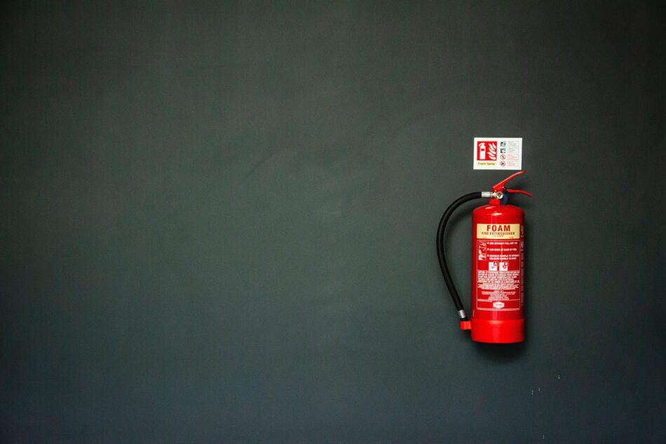 red foam fire extinguisher on black wall.
