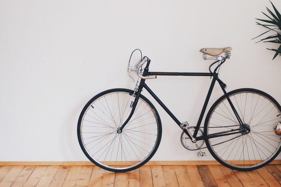 black road bicycle inside house next to white wall.