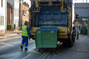 bin lorry or waste truck collects refuse from a green dumpster