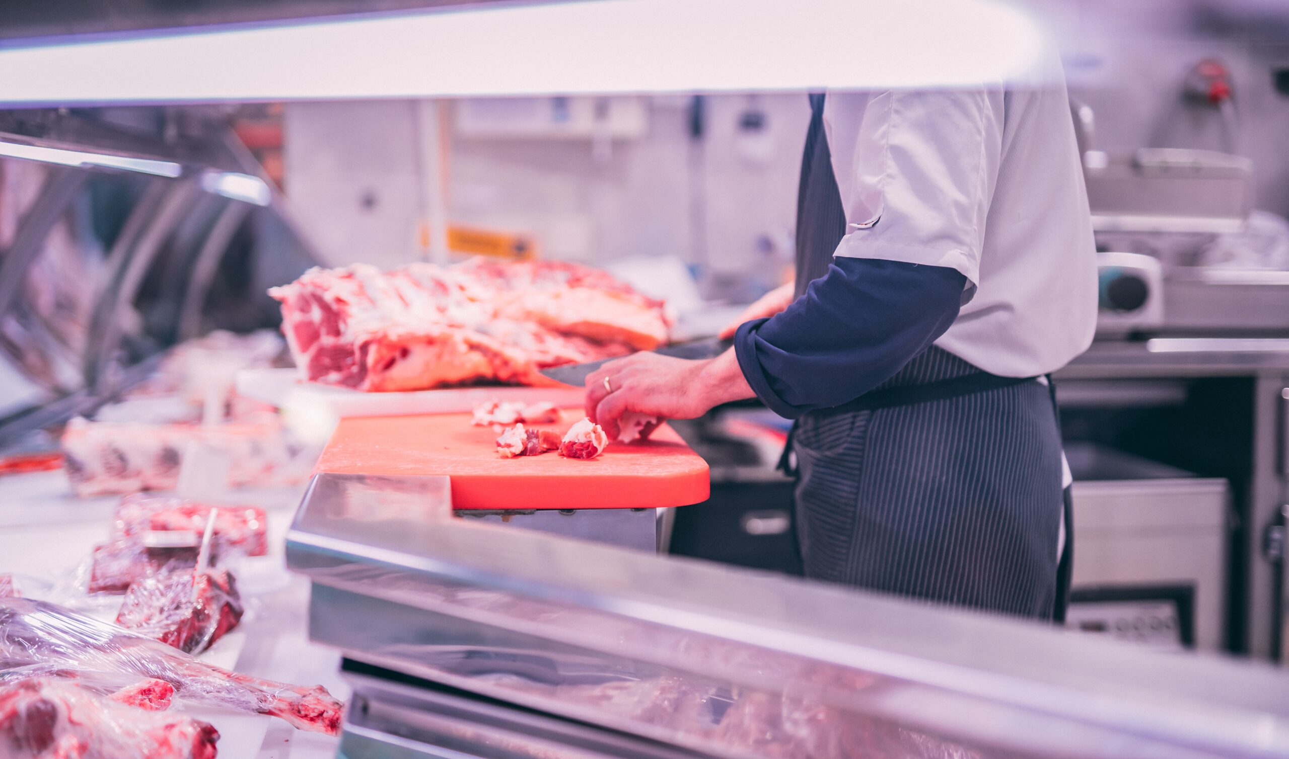 meat preparation behind butchers display.