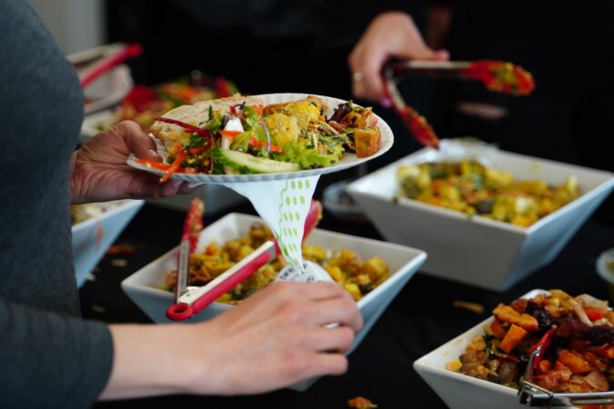 woman putting food on a plate from catering.