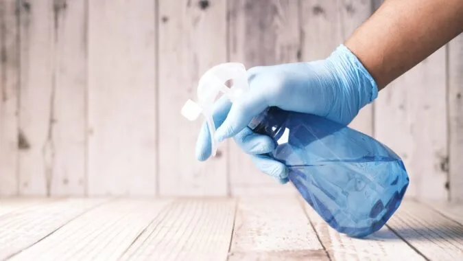 hand spraying cleaning bottle onto wood.