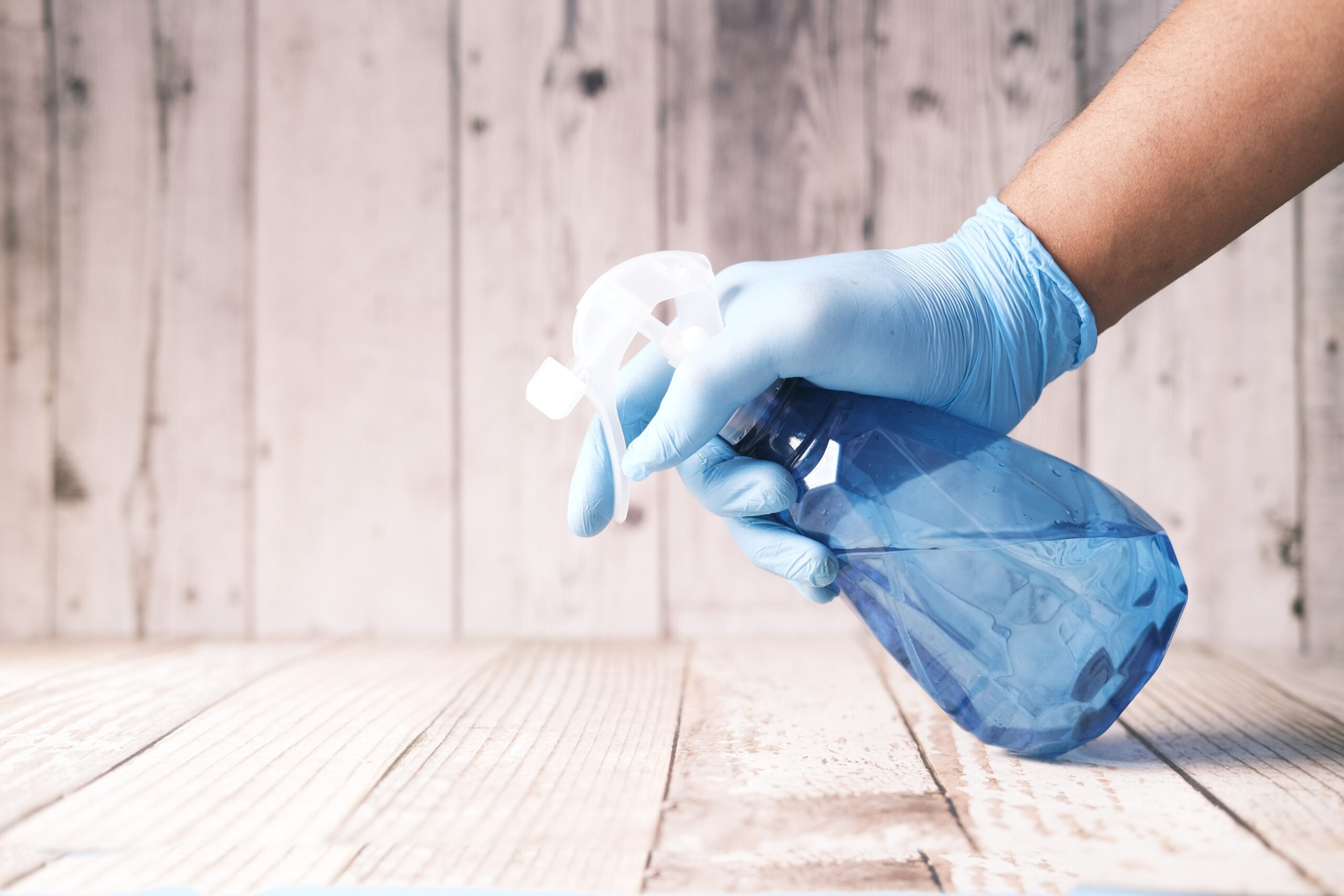 hand spraying cleaning bottle onto wood.