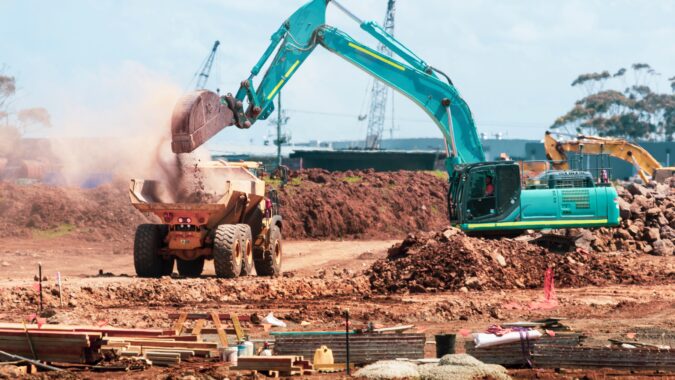 digger dropping rubble into truck.