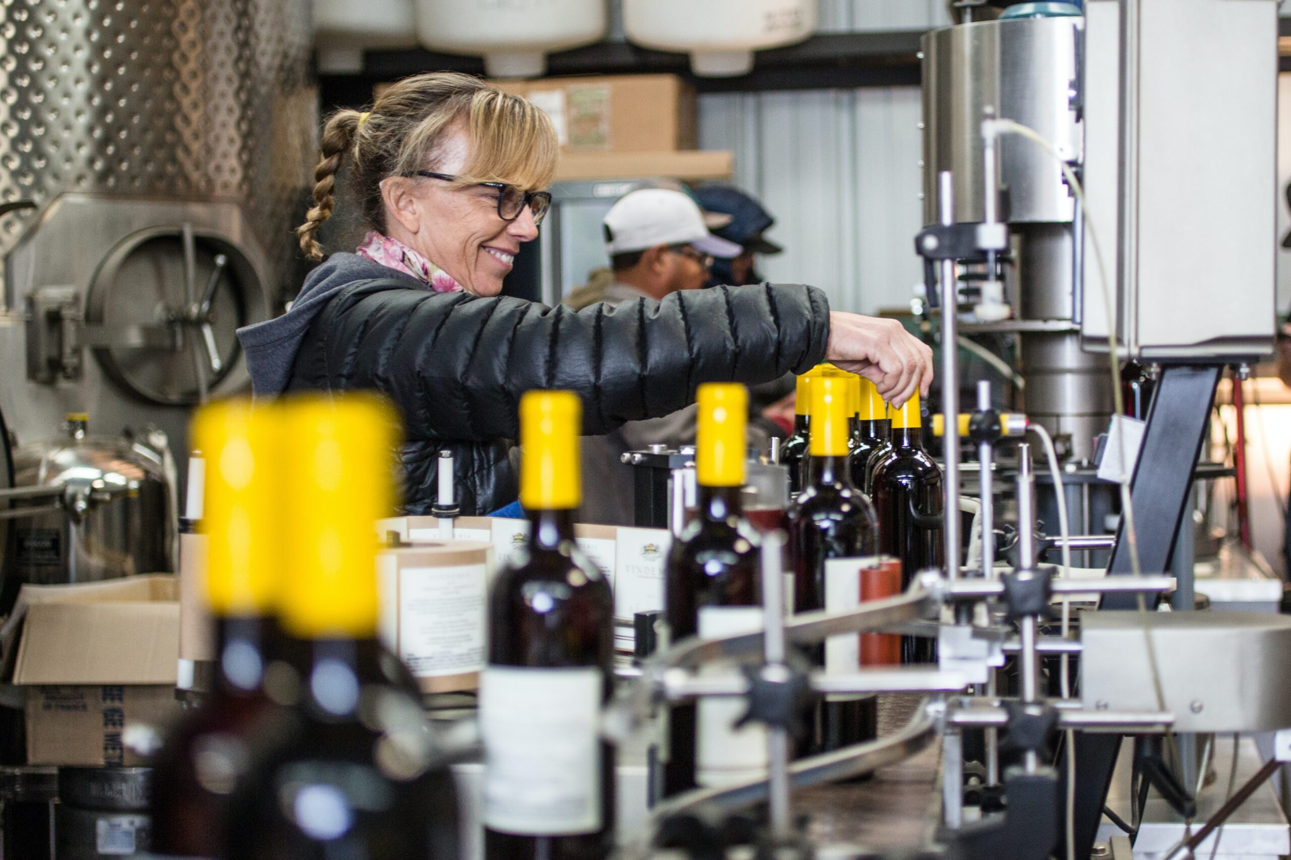 woman bottling wine in factory.