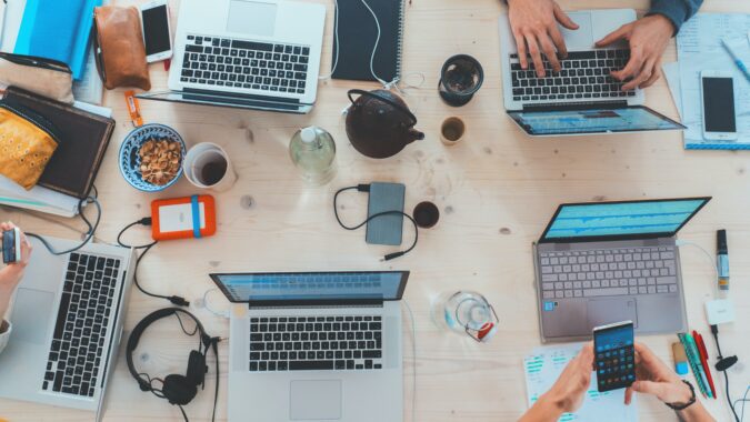 overhead view of laptops and phones on table.
