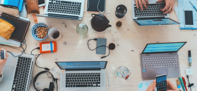 overhead view of laptops and phones on table.
