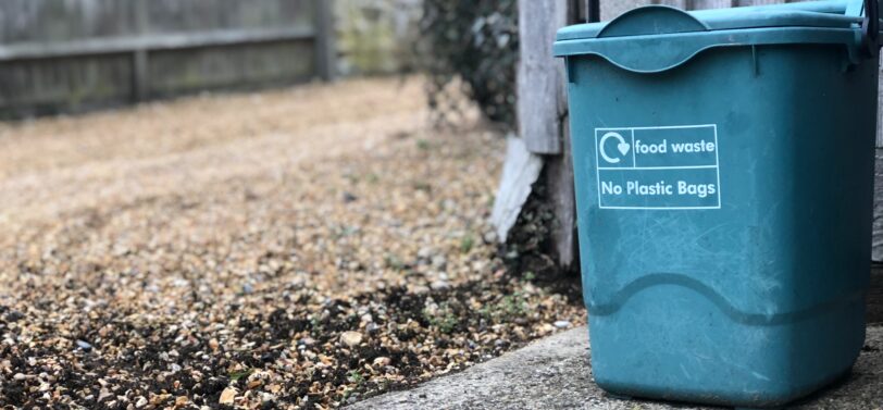 food waste bin in front of wooden fence.
