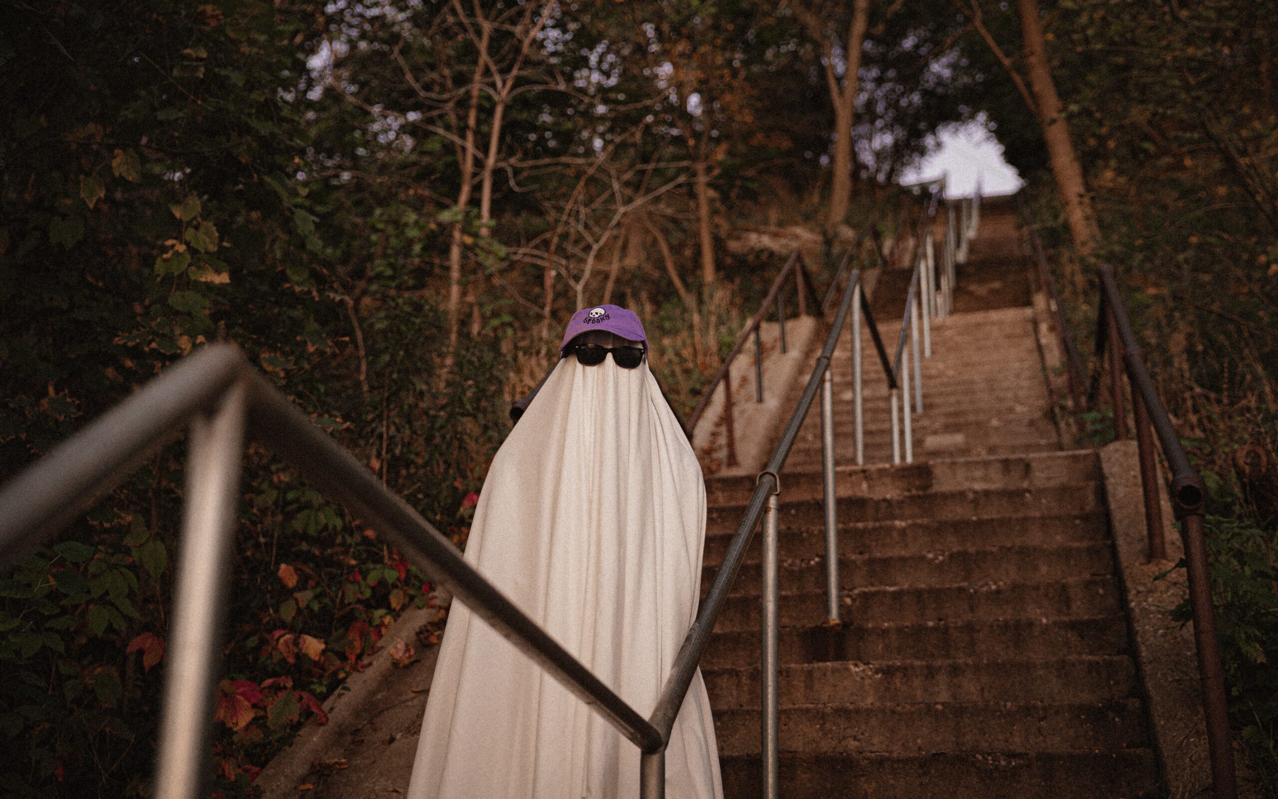 ghost costume stood on stairs wearing sunglasses.