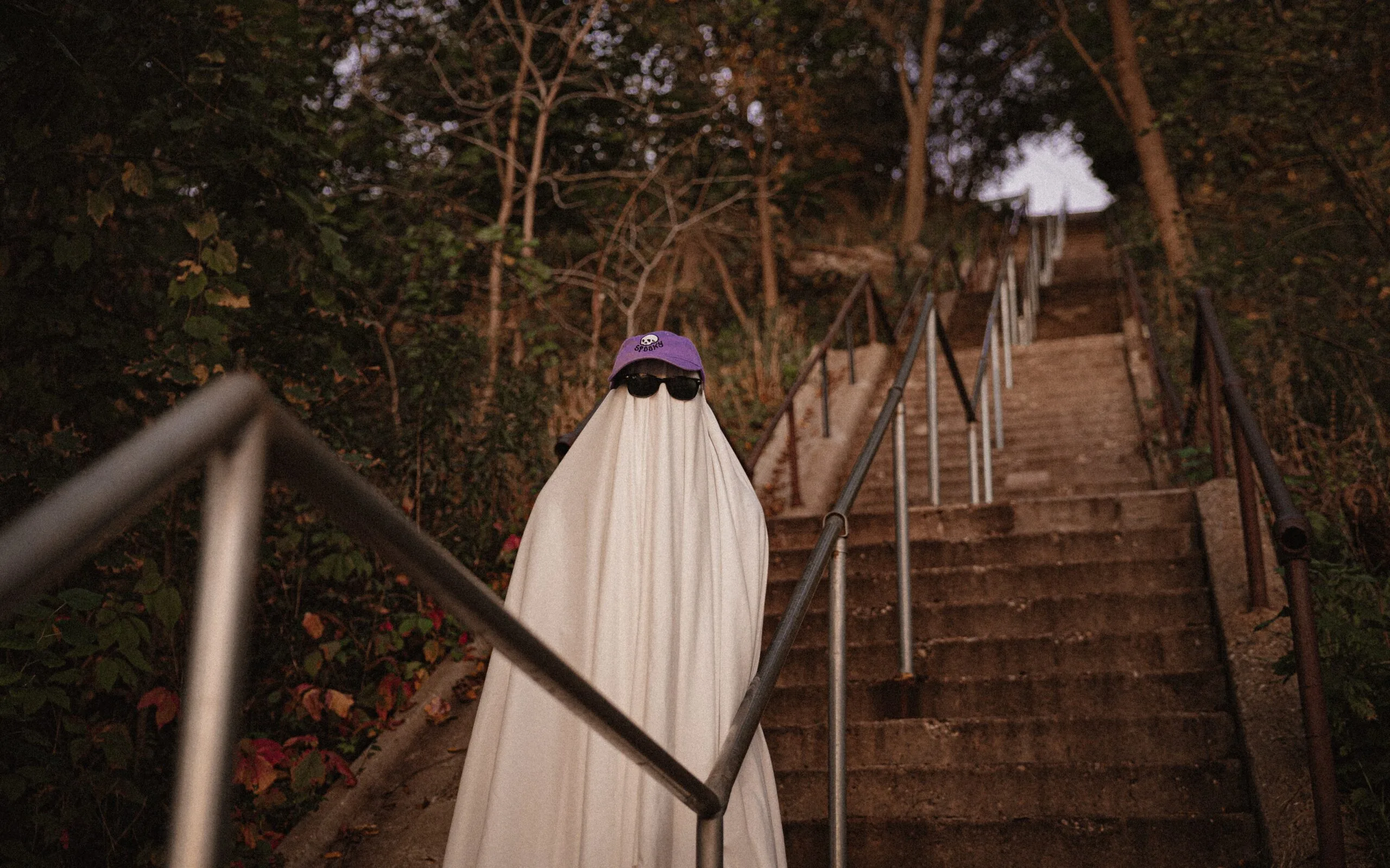 ghost costume stood on stairs wearing sunglasses.