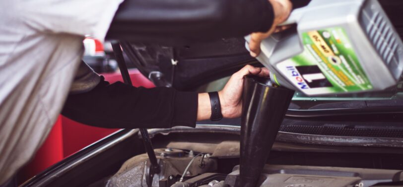 man pouring oil into car engine.