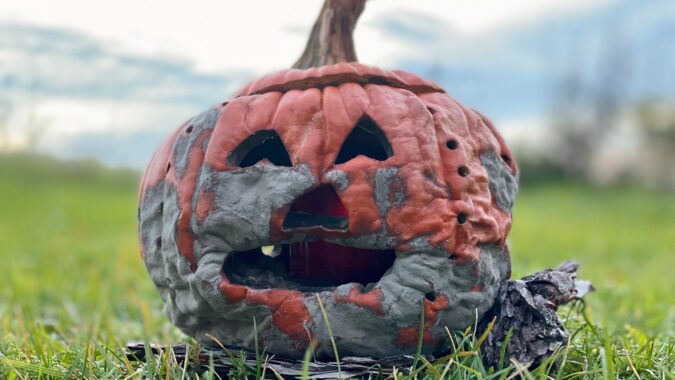 old halloween pumpkin starting to rot on grass.