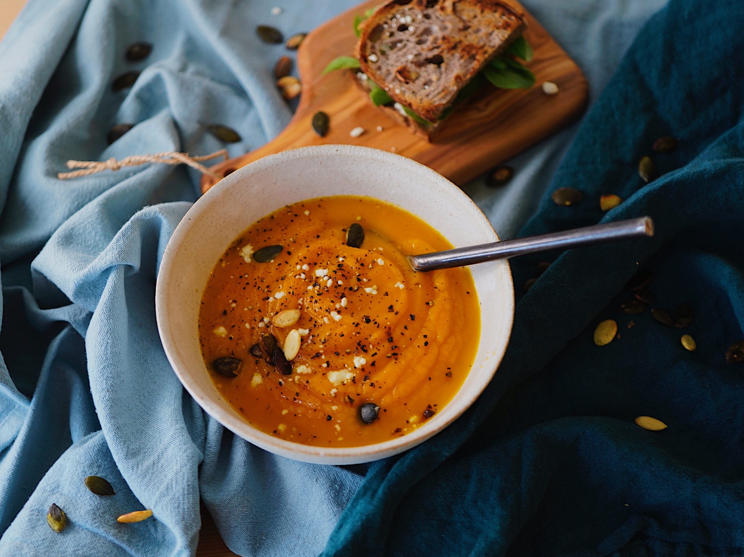 bowl of pumpkin soup with slice of brown bread.