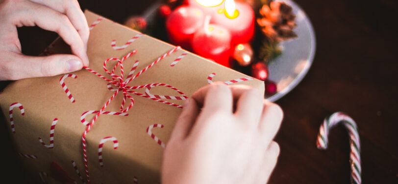 christmas present in hands with candles in background.