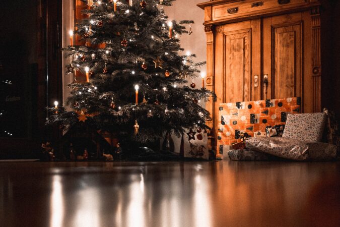 Christmas tree lit up in home next to cupboard.