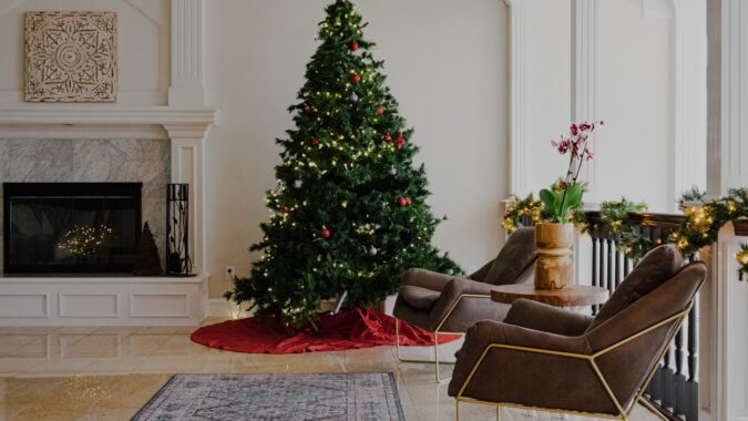 Christmas tree next to rug and fireplace.