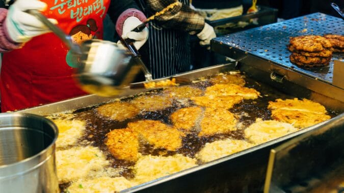 cooking oil poured onto food frying in commercial kitchen.