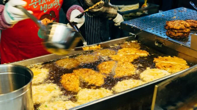 cooking oil poured onto food frying in commercial kitchen.