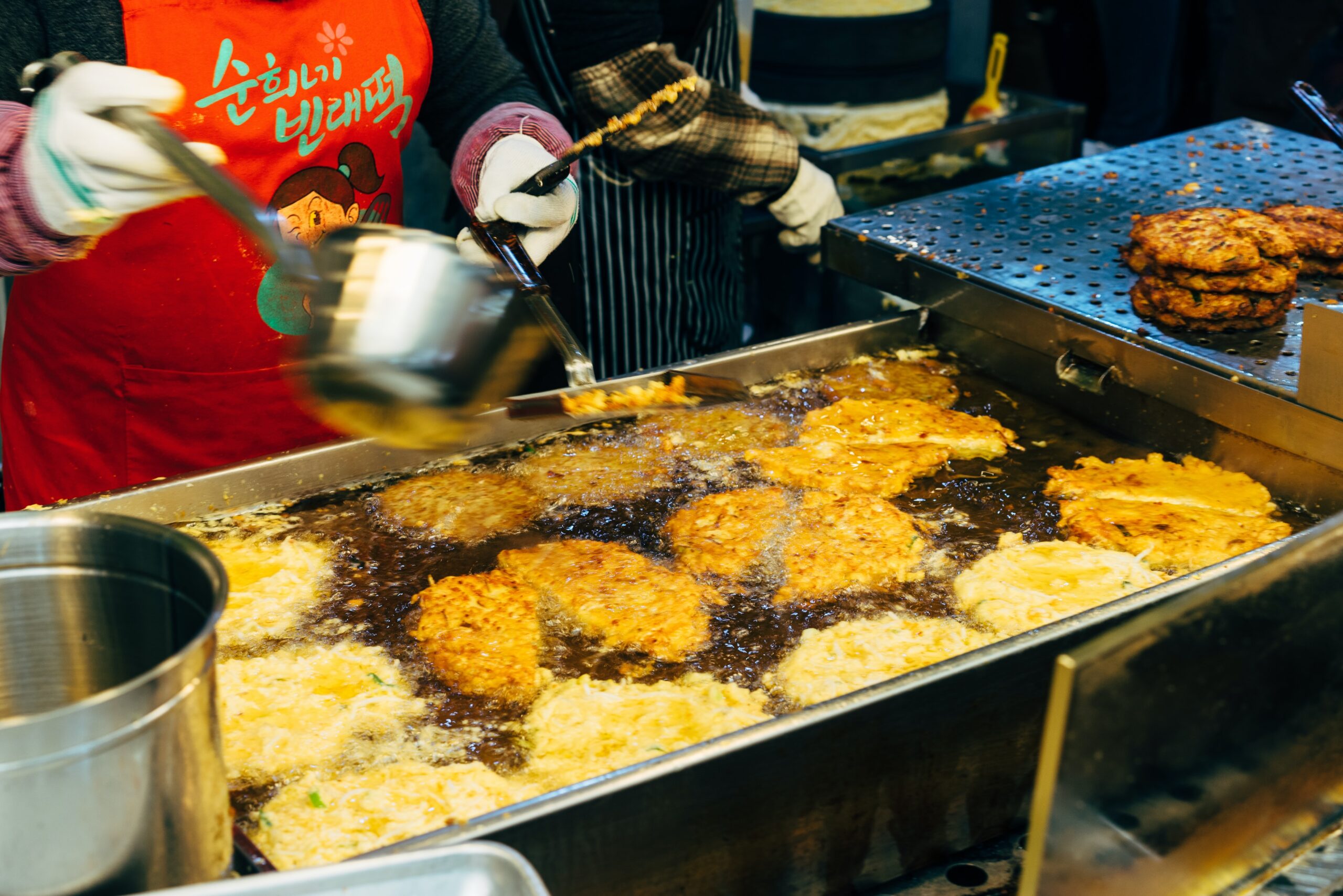 cooking oil poured onto food frying in commercial kitchen.