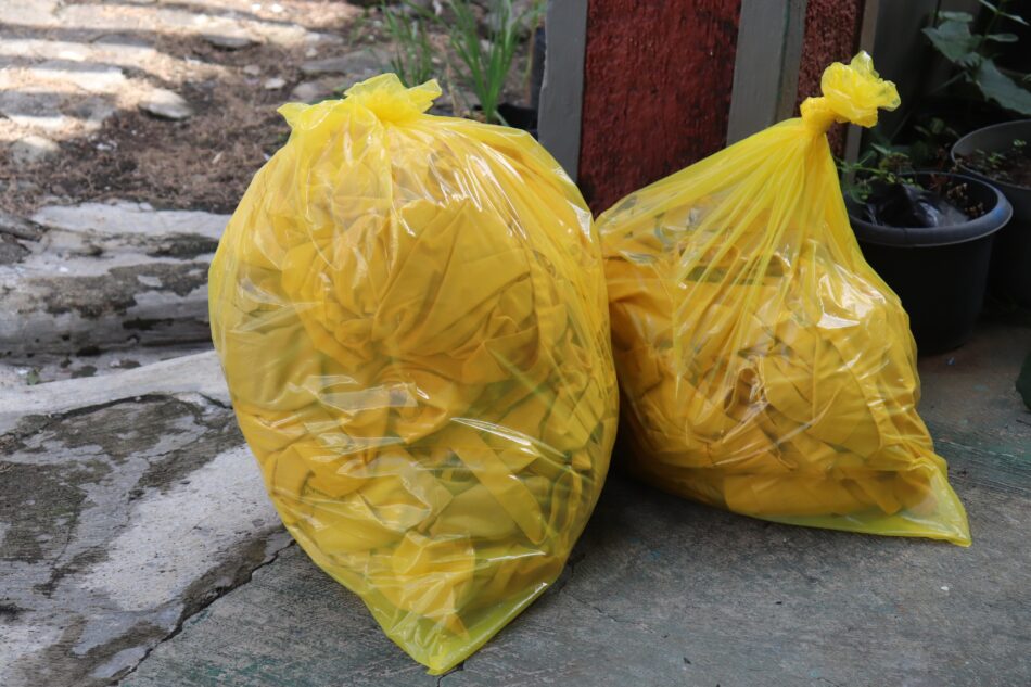 two yellow clinical waste bags full or rubbish.