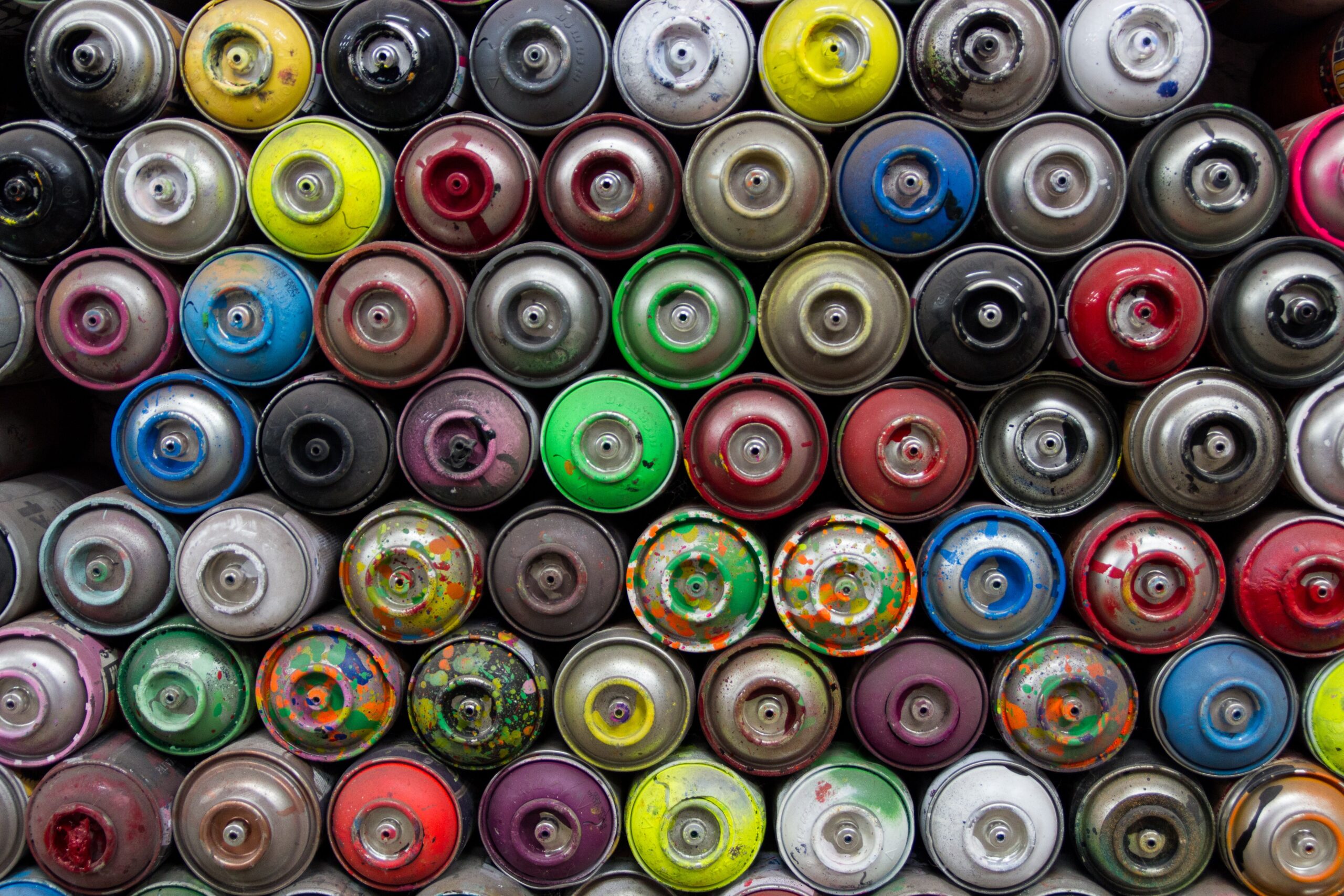overhead view of tops of colourful aerosol paint cans.