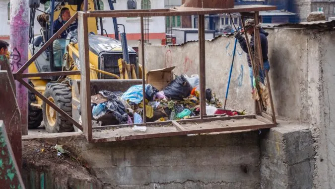 digger pushing waste bags on construction site.