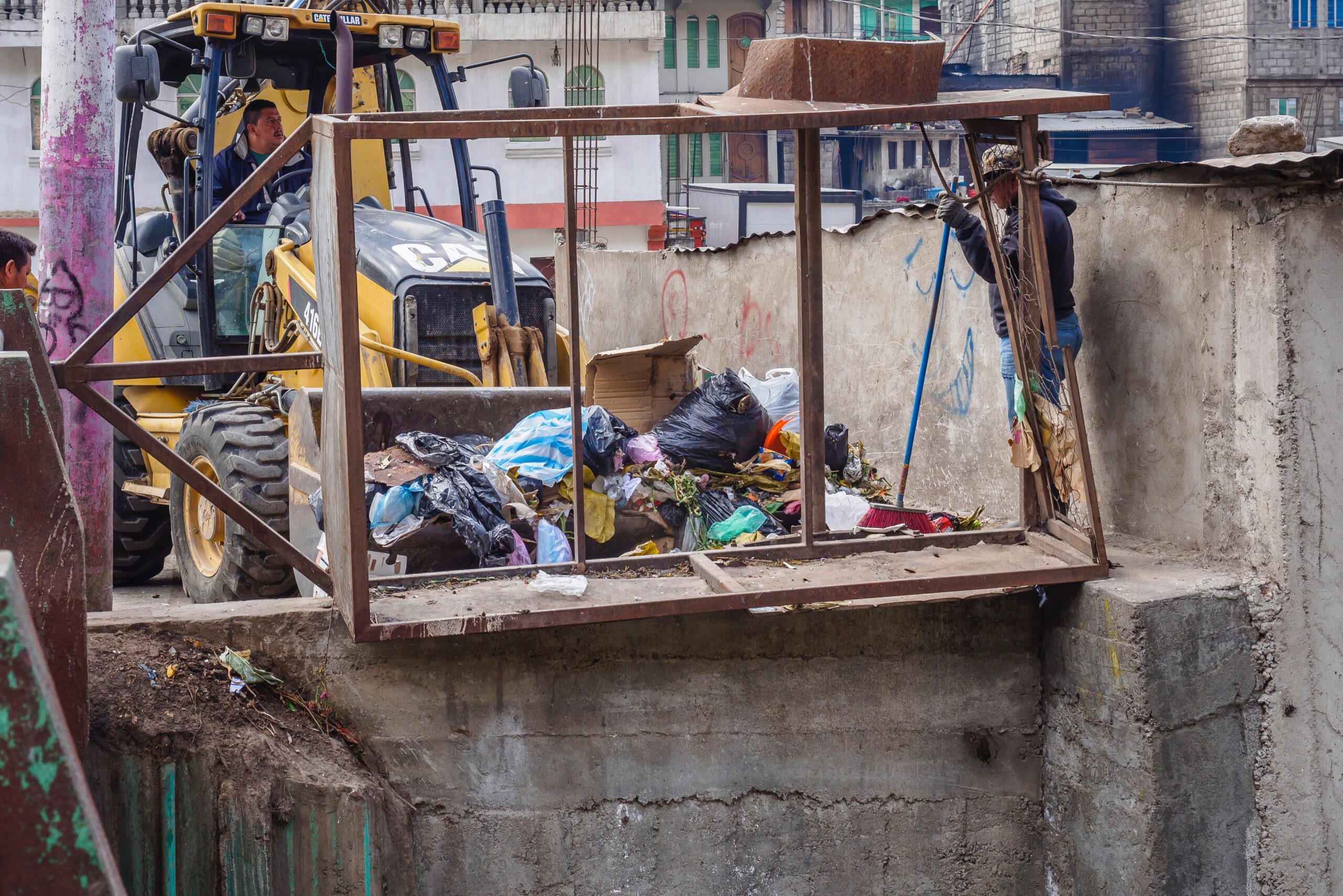 digger pushing waste bags on construction site.