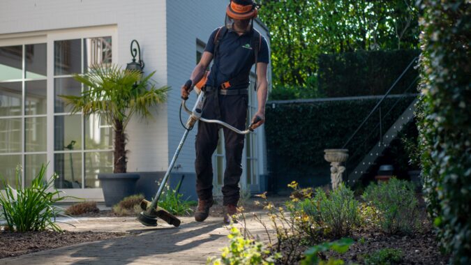 man with strimmer and protective gear.