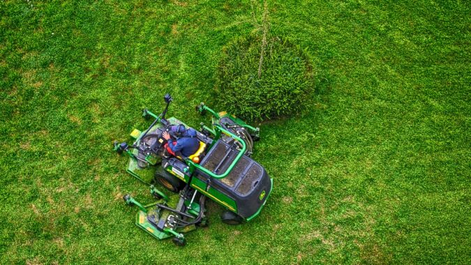 ride on lawnmower from above circling a tree.