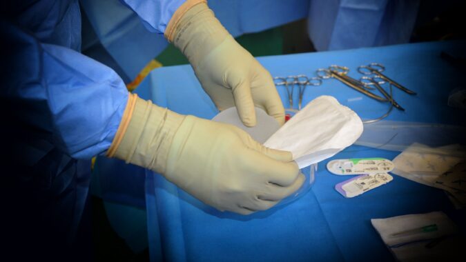 doctor's hands in gloves holding mask.