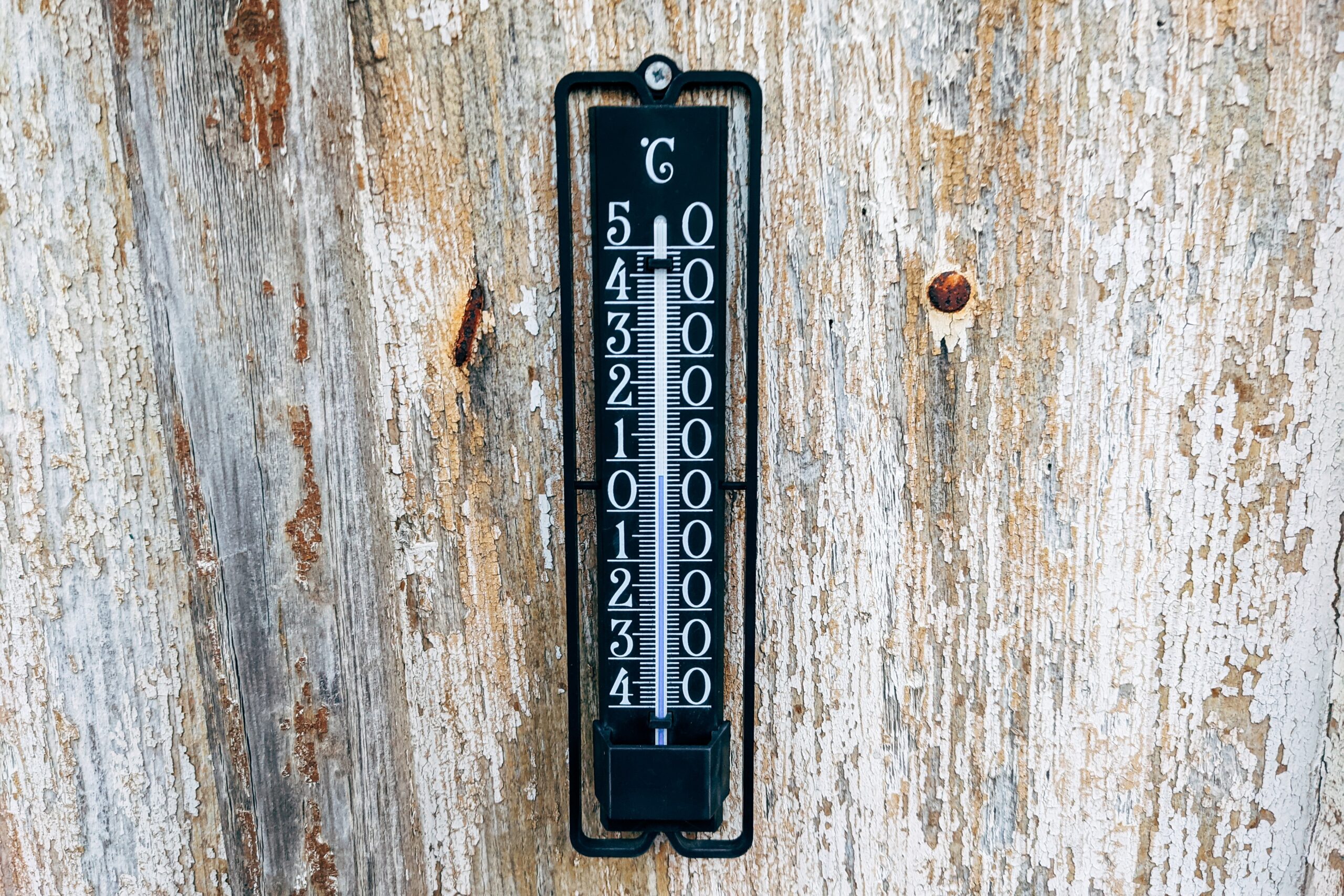 mercury thermometer attached to a wooden fence.