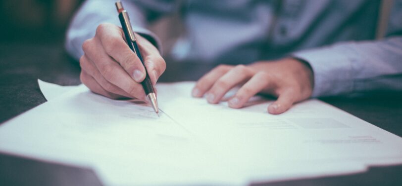 man writing on sheet of paper.