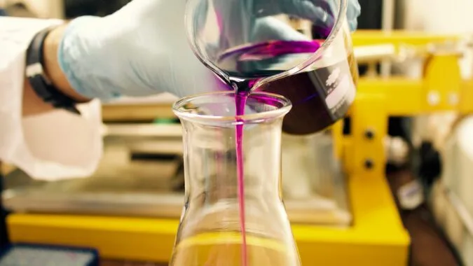 chemical poured into lab container.
