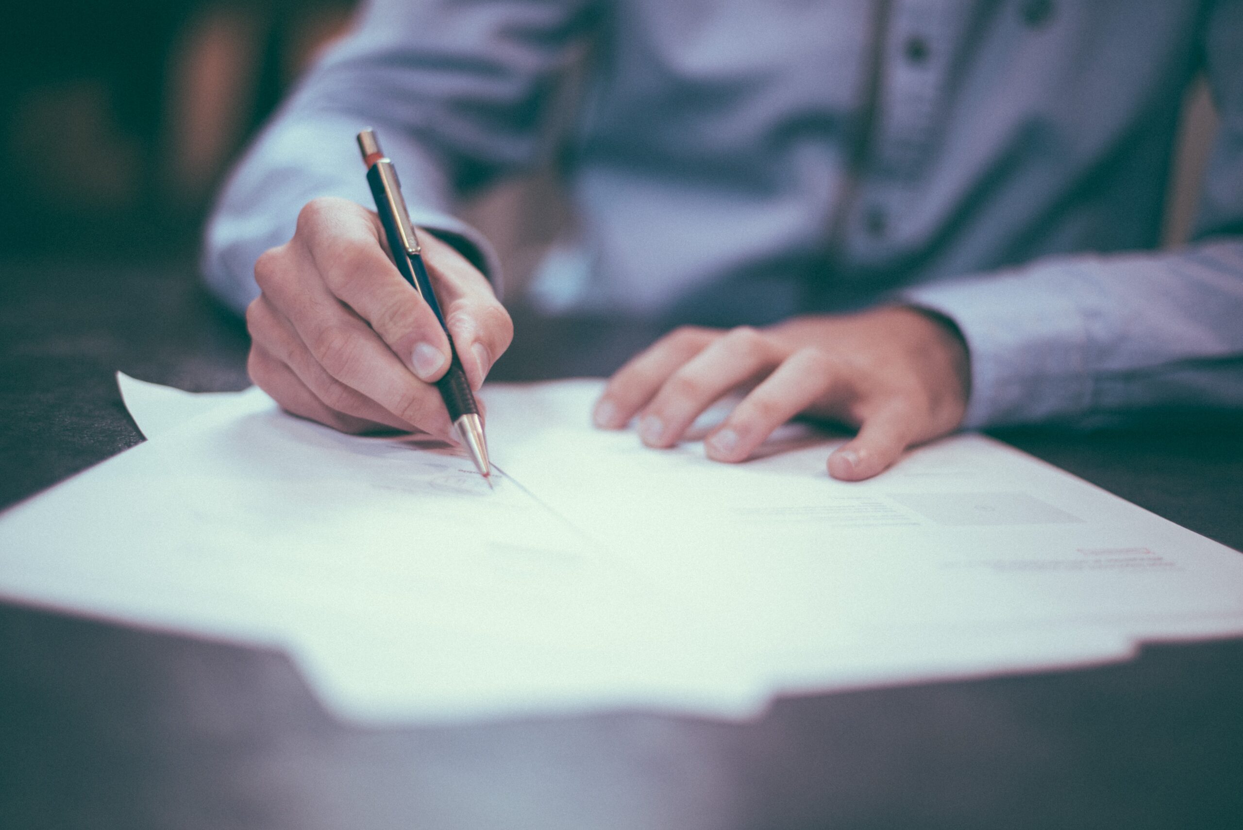 man writing on sheet of paper.