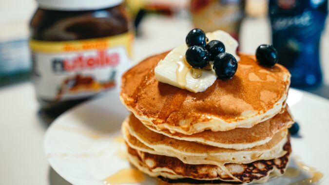 pancakes with blueberries on top and Nutella jar in background.