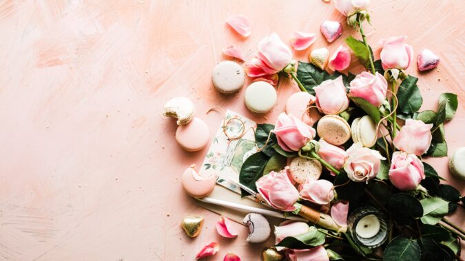 flowers candles and macaroons spread out.