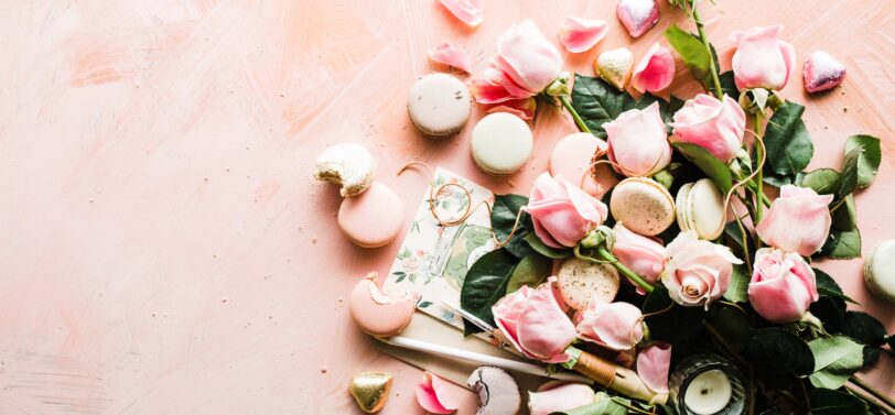 flowers candles and macaroons spread out.