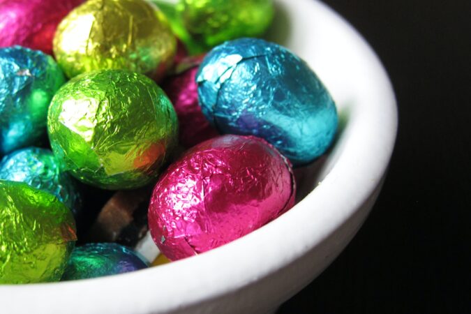 small chocolate eggs in coloured foil in bowl.