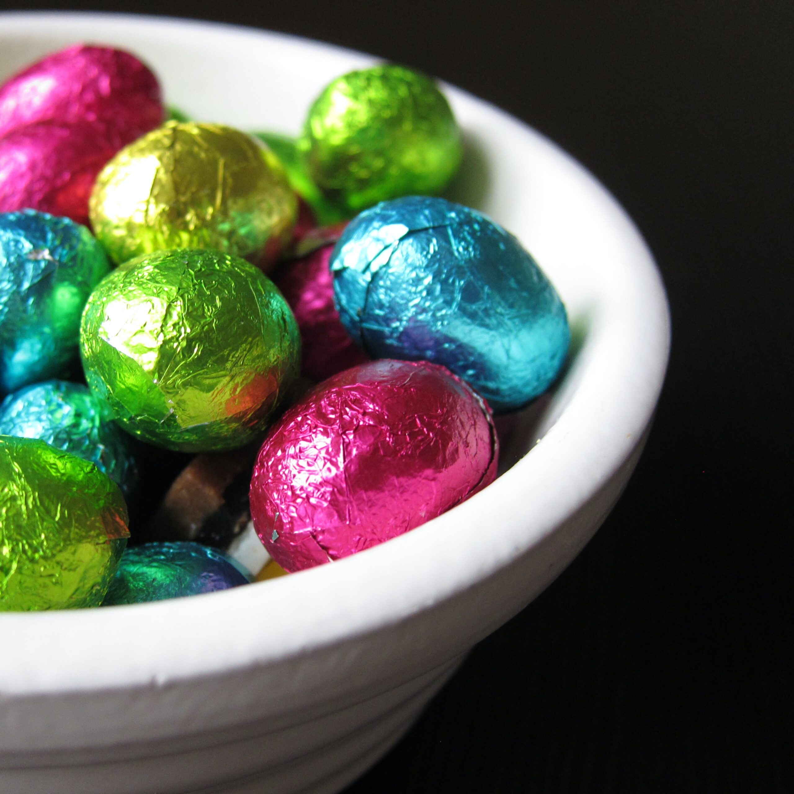 small chocolate eggs in coloured foil in bowl.