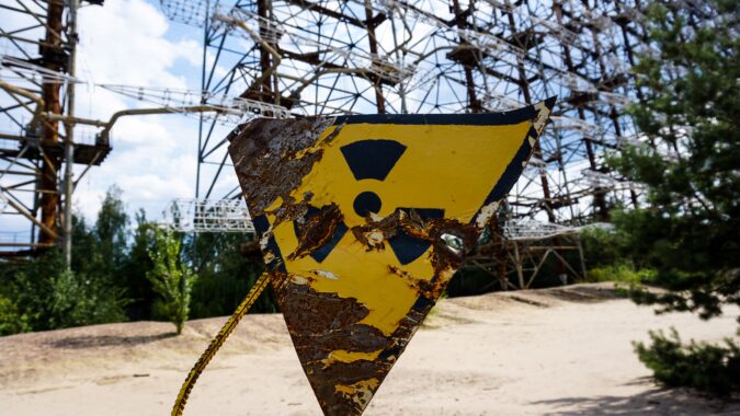 nuclear waste sign on fence in front of power plant.