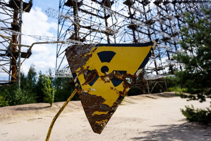 nuclear waste sign on fence in front of power plant.
