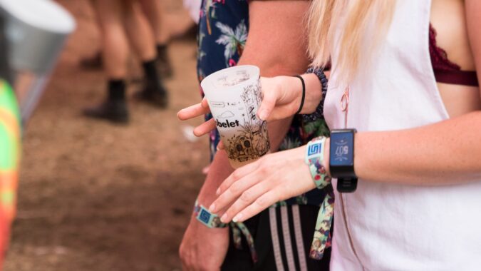 woman with plastic cup of beer dancing at a festival.