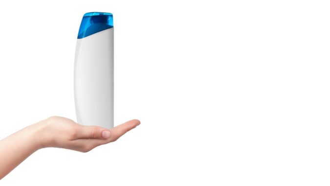 white HDPE plastic shampoo bottle held out on a hand.