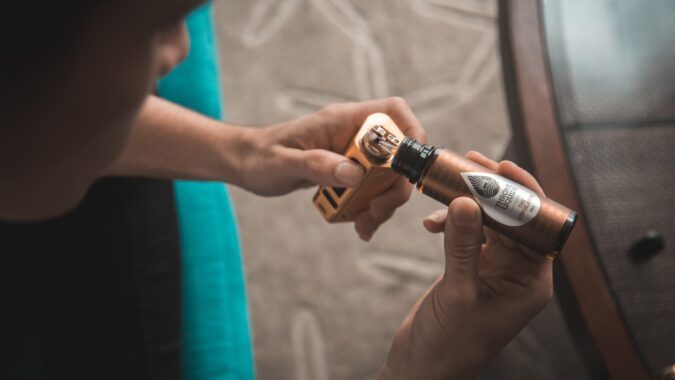 hands of person refilling a vape.