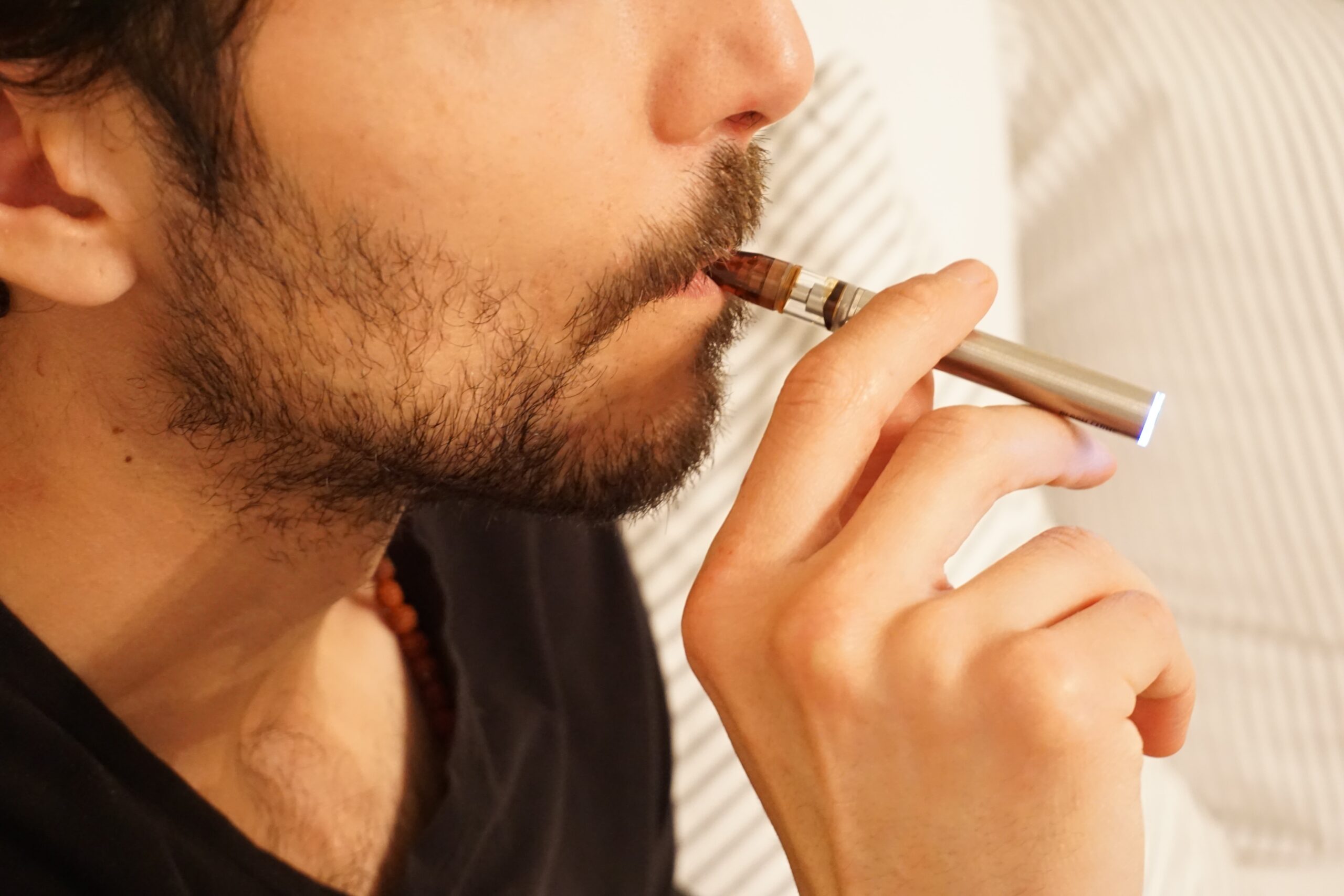 man smoking a vape with one hand.