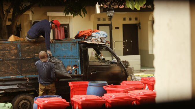 bin men loading waste into truck on street.