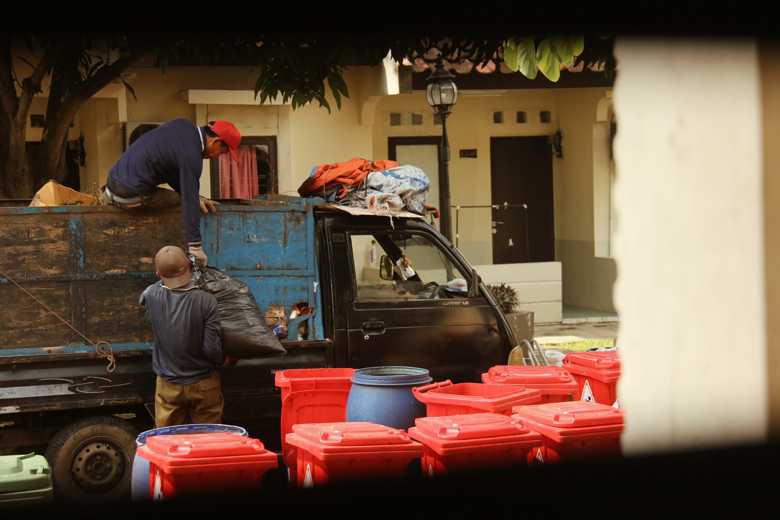 bin men loading waste into truck on street.