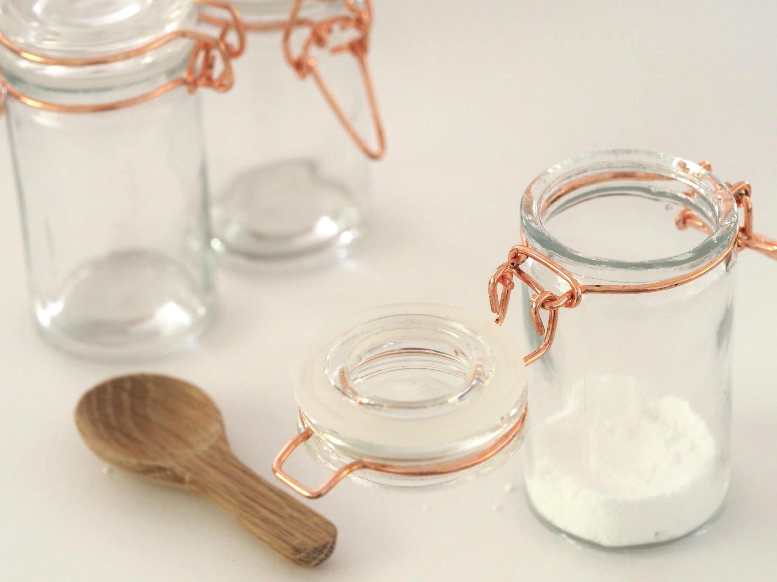 one empty glass jar one with flour in and a wooden spoon.